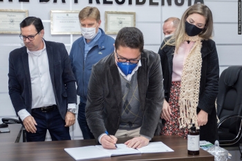 Emerson Vilanova assina o termo de posse ao lado da esposa Andréa; ao fundo, Alécio Espínola (esq.) e Nelsinho Padovani