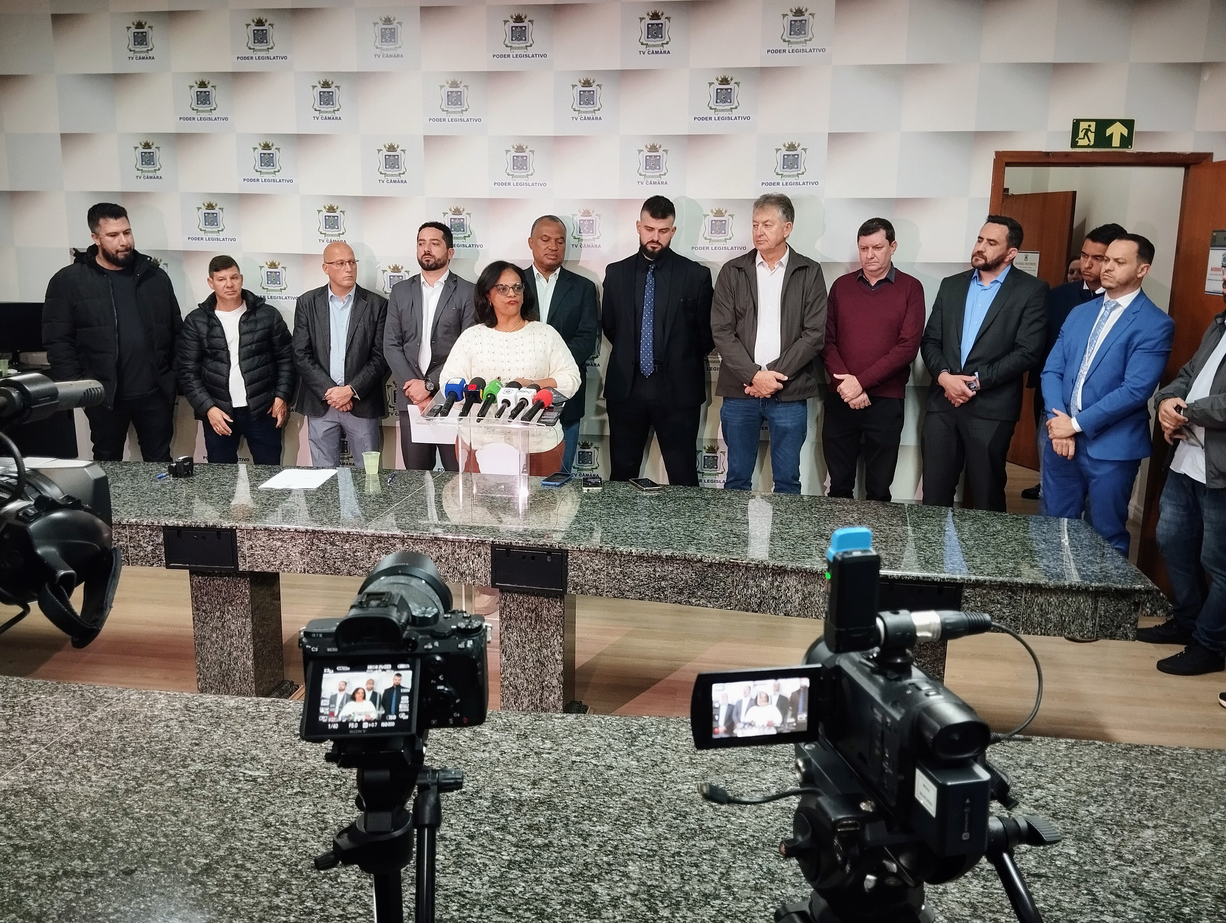 Secretária Beth Leal fala à imprensa, acompanhada pelo presidente Tiago Almeida e mais dez vereadores