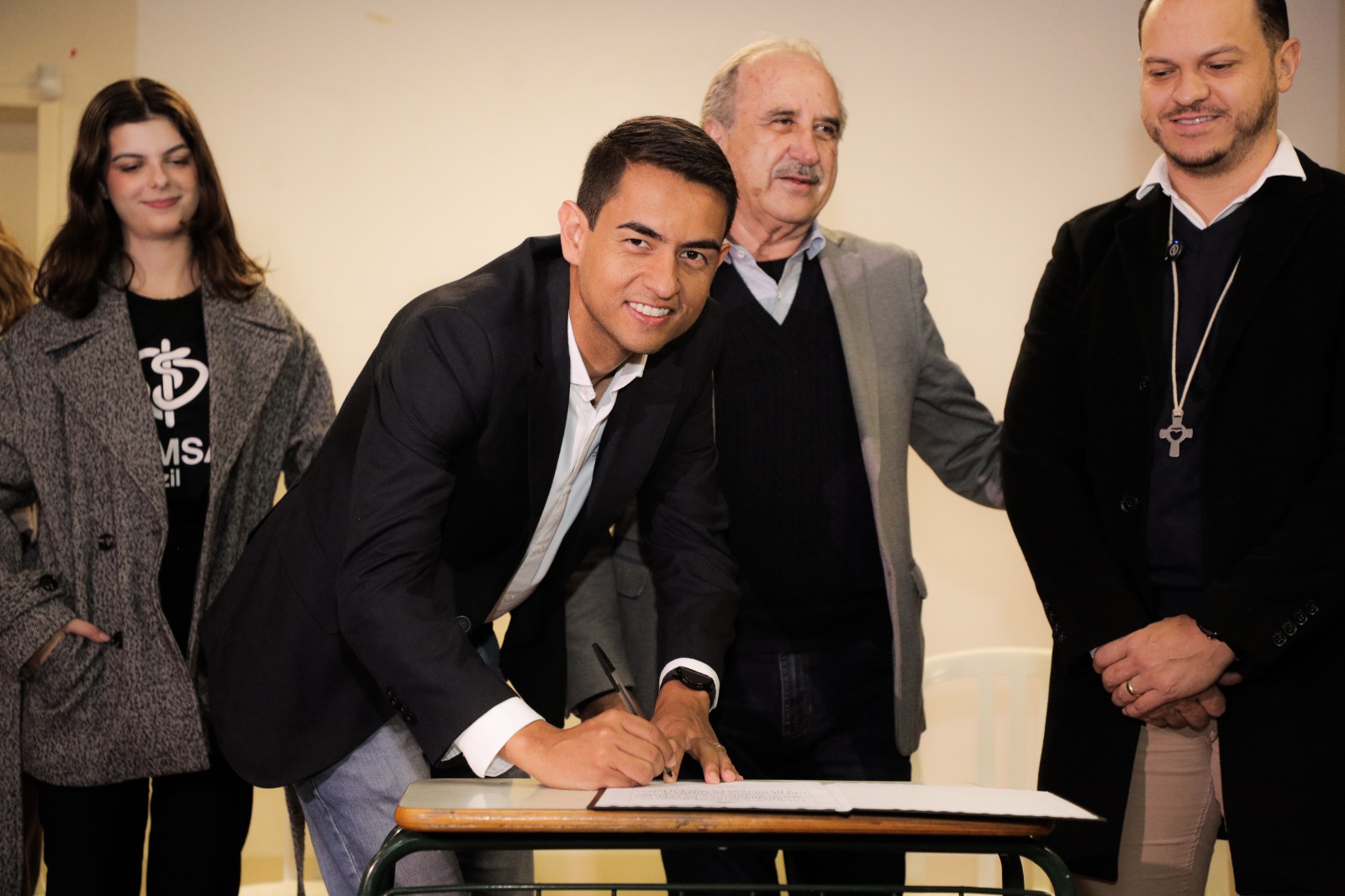Hudson Moreschi assina logo após a sanção do prefeito Renato Silva (ao fundo)