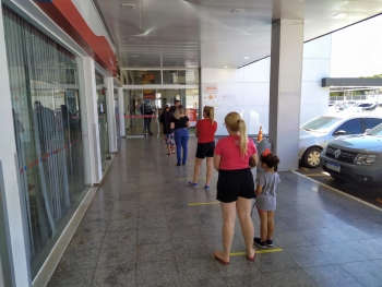 Clientes obedecem limite de distância em fila na entrada de um supermercado na sexta-feira (27)