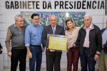 O homenageado Arnaldo Curioni, ao centro, recebe o título do presidente Alécio Espínola, acompanhado dos proponentes Seno Rohden (esq.) e Jadir de Mattos (dir.), e também da vereadora Nadir Lovera